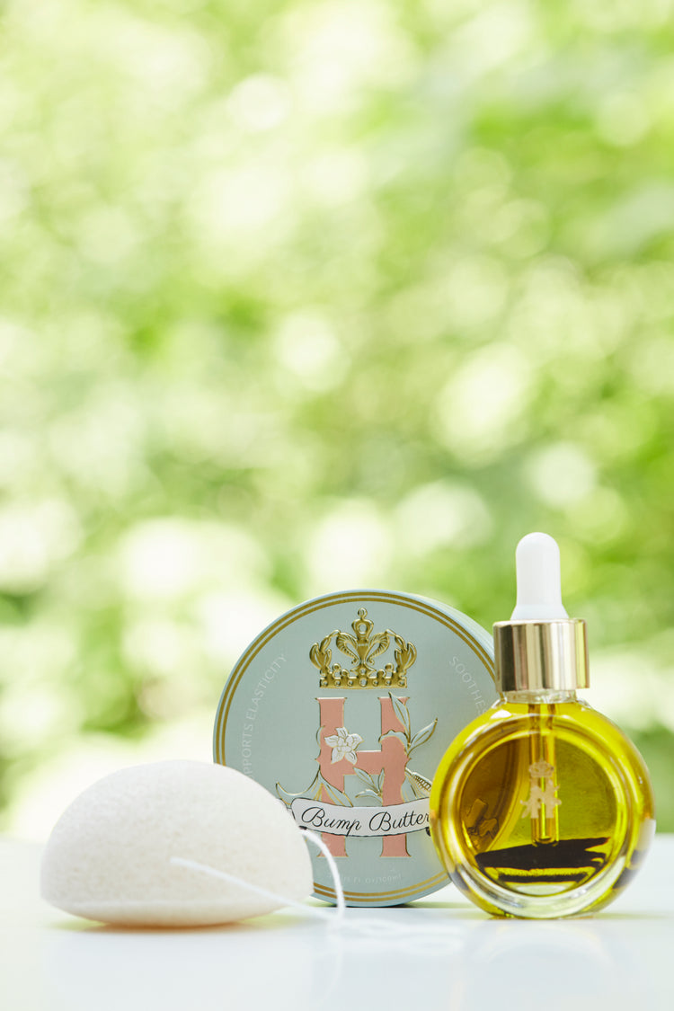 Bump Butter tin, a konjac sponge and a serum bottle in front of green foliage