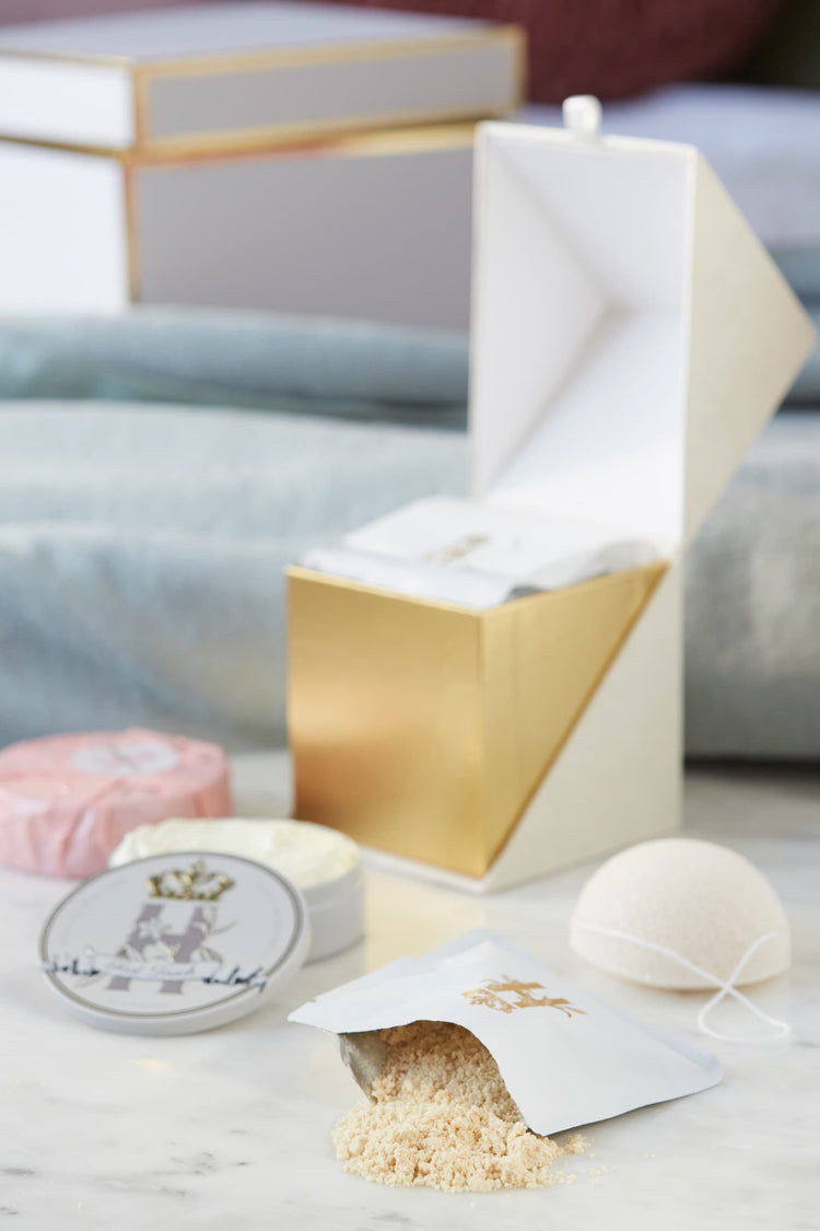 Open gold-lined ritual box with a soak pouch, a tin and a konjac sponge