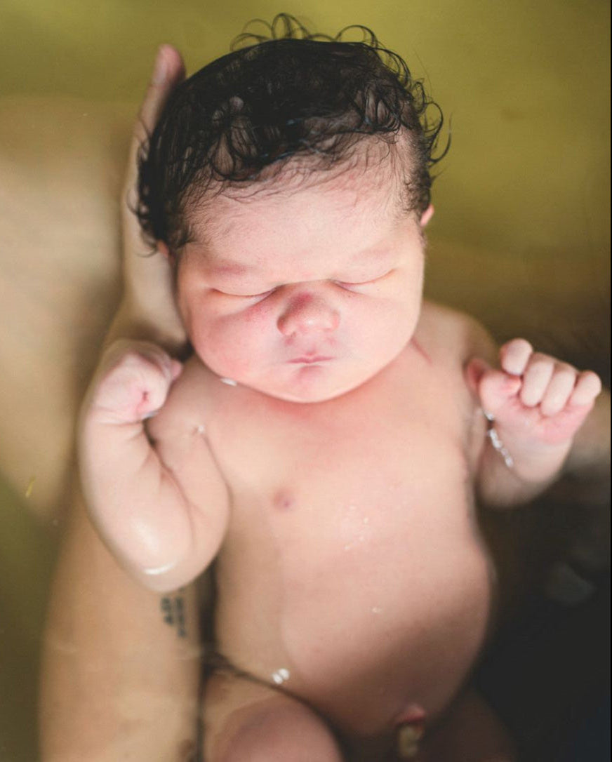 Newborn baby floating peacefully in a warm herbal bath, supported by a parent’s hands. A calming postpartum ritual that nurtures the baby’s delicate skin and promotes bonding. Ideal for content on newborn skincare, natural baby baths, and holistic postpartum care.
