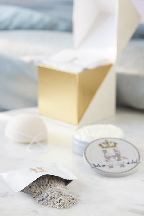 Open ritual box with a grey soak pouch spilling powder, a konjac sponge and a tin