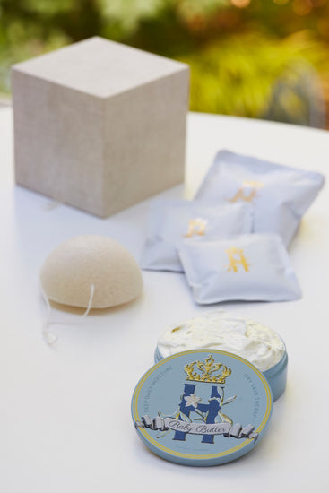 Linen gift box, light blue soak sachets, a konjac sponge and a Butter in Blue tin on a white table