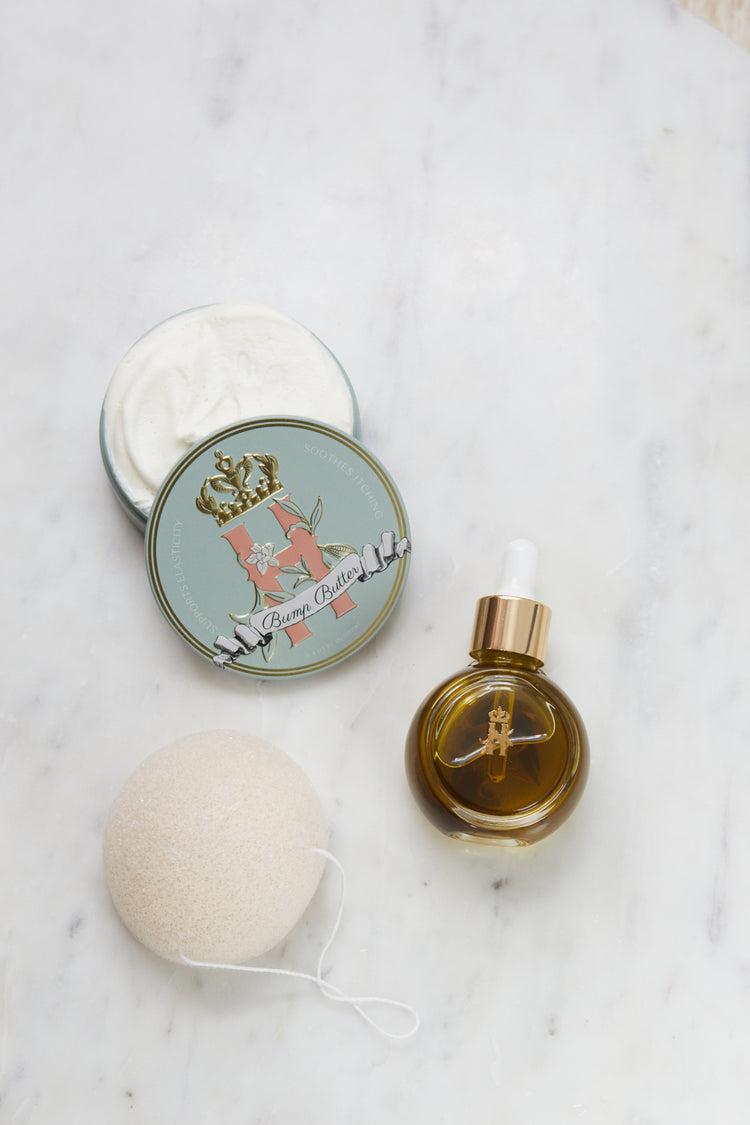 Bump Butter tin, an open tin of butter, a serum bottle and a konjac sponge on marble