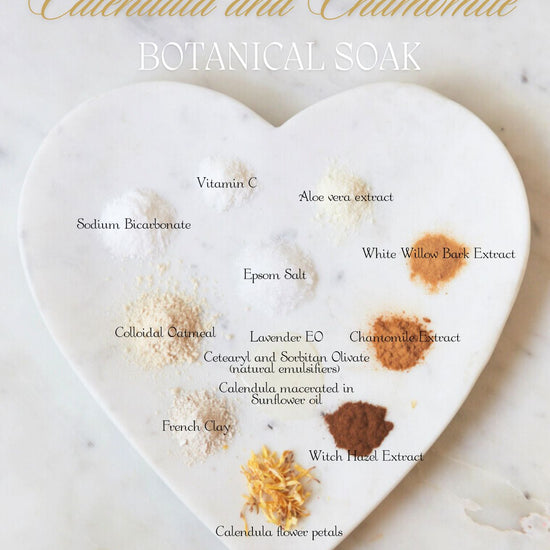 Calendula and Chamomile Botanical Soak ingredients arranged on a heart-shaped marble slab, each labeled by name