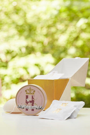 Butter in Pink tin and soak sachets beside an open gold ritual box outdoors
