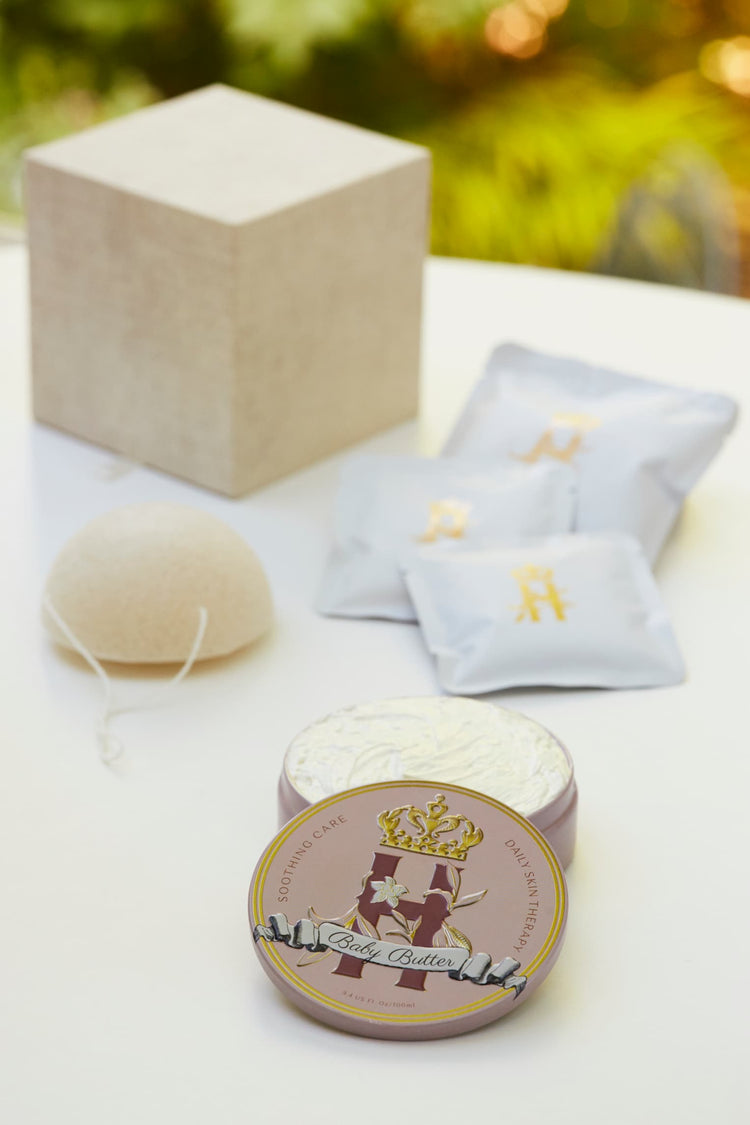 Linen gift box, soak sachets, a konjac sponge and a Butter in Pink tin on a white table