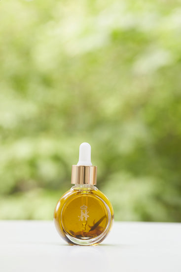 Serum bottle with a gold dropper in front of green foliage