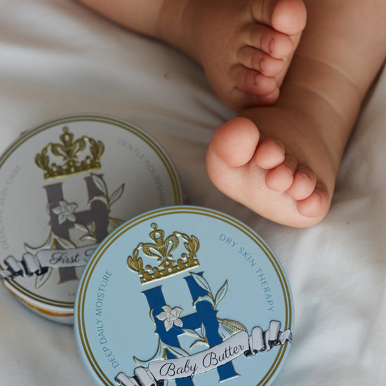 Butter in Blue tin beside a baby's bare feet on white bedding
