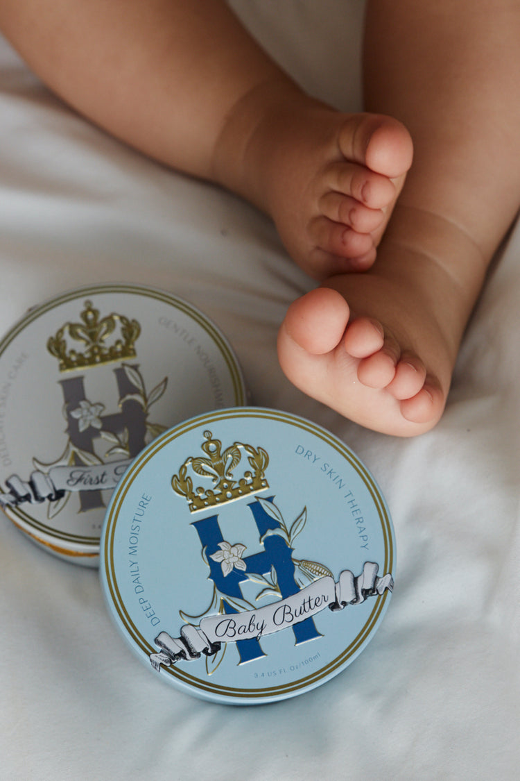 Butter in Blue tin beside a baby's bare feet on white bedding