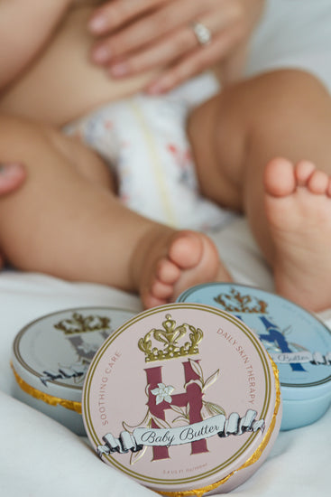 Baby's legs and feet in a diaper with Butter in Pink and Butter in Blue tins in front
