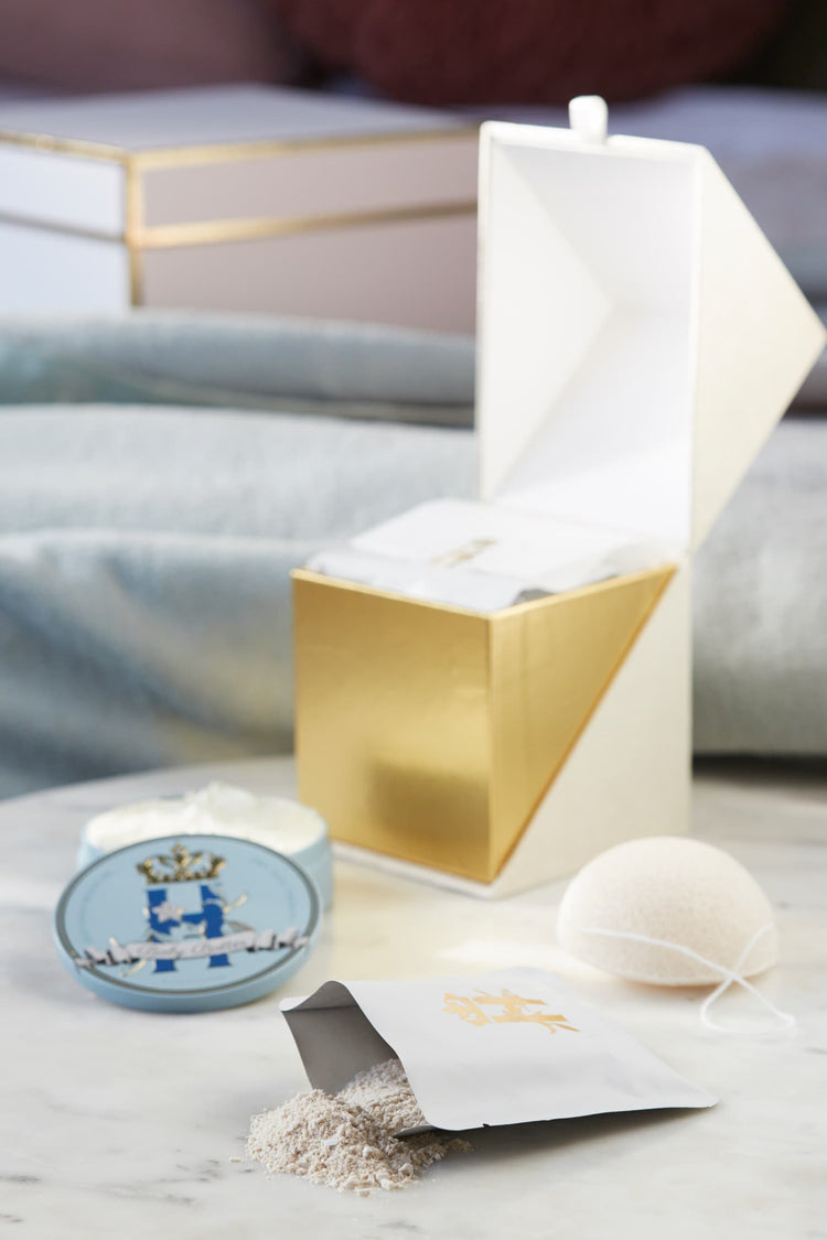 Open gold ritual box with a blue tin, a konjac sponge and a spill of soak powder