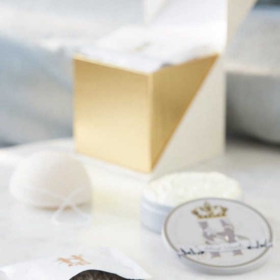 Open ritual box with a grey soak pouch spilling powder, a konjac sponge and a tin