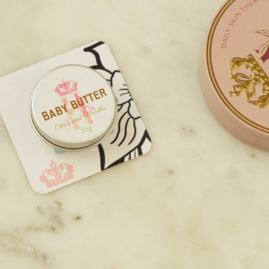 Baby Butter pocket-size tin in pink on a printed card beside the full-size pink tin