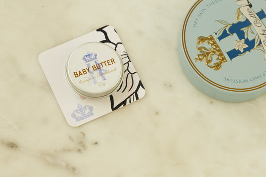Baby Butter pocket-size tin in blue on a printed card beside the full-size blue tin