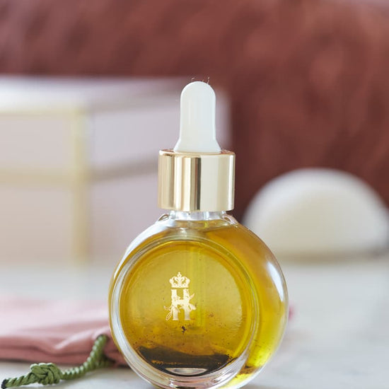 Rejuvenating Serum in a round glass bottle with a white dropper on a marble table