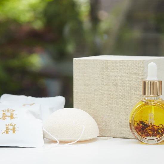 Linen gift box, soak sachets, a konjac sponge and a serum bottle with rose petals outdoors