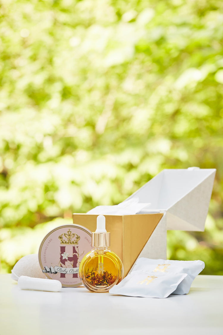 Serum bottle, Butter in Pink tin and an open gold box with a soak sachet in sunlit greenery