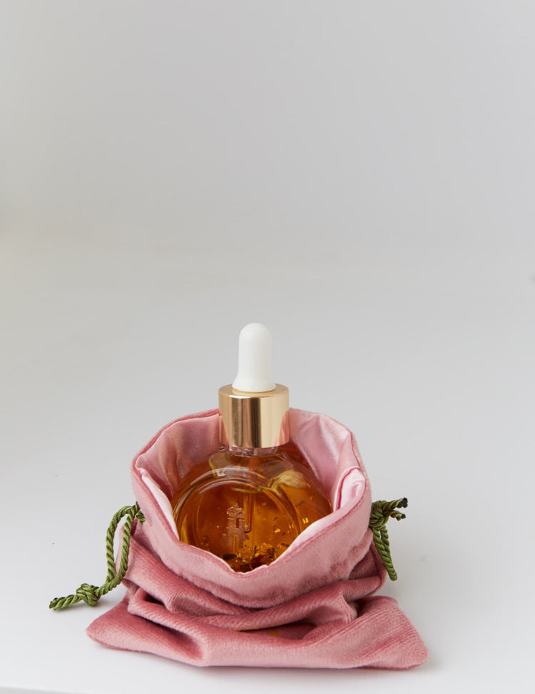 Rose Ritual Facial Serum in a round glass bottle inside a pink velvet pouch