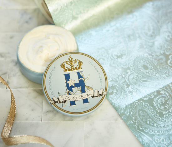 Butter in Blue tin with a gold crown beside an open tin of whipped butter on turquoise brocade