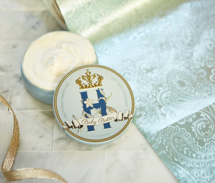 Butter in Blue tin with a gold crown beside an open tin of whipped butter on turquoise brocade