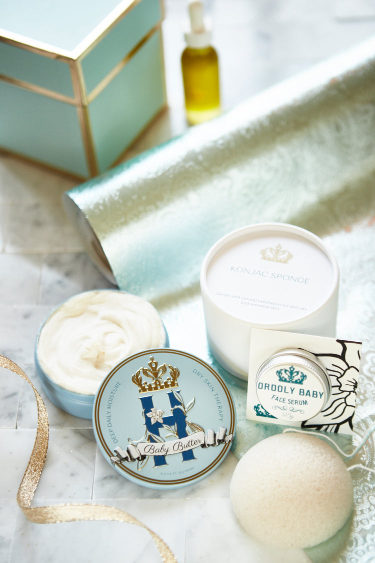 Butter in Blue tin with a konjac sponge, an open tin of butter and a serum bottle on a glass tray