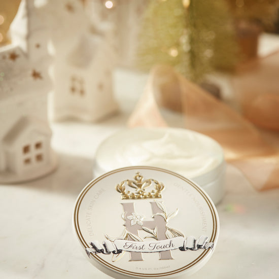 First Touch tin in front of an open container of whipped butter, with small white ceramic houses behind