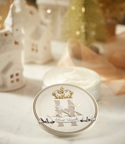 First Touch tin in front of an open container of whipped butter, with small white ceramic houses behind