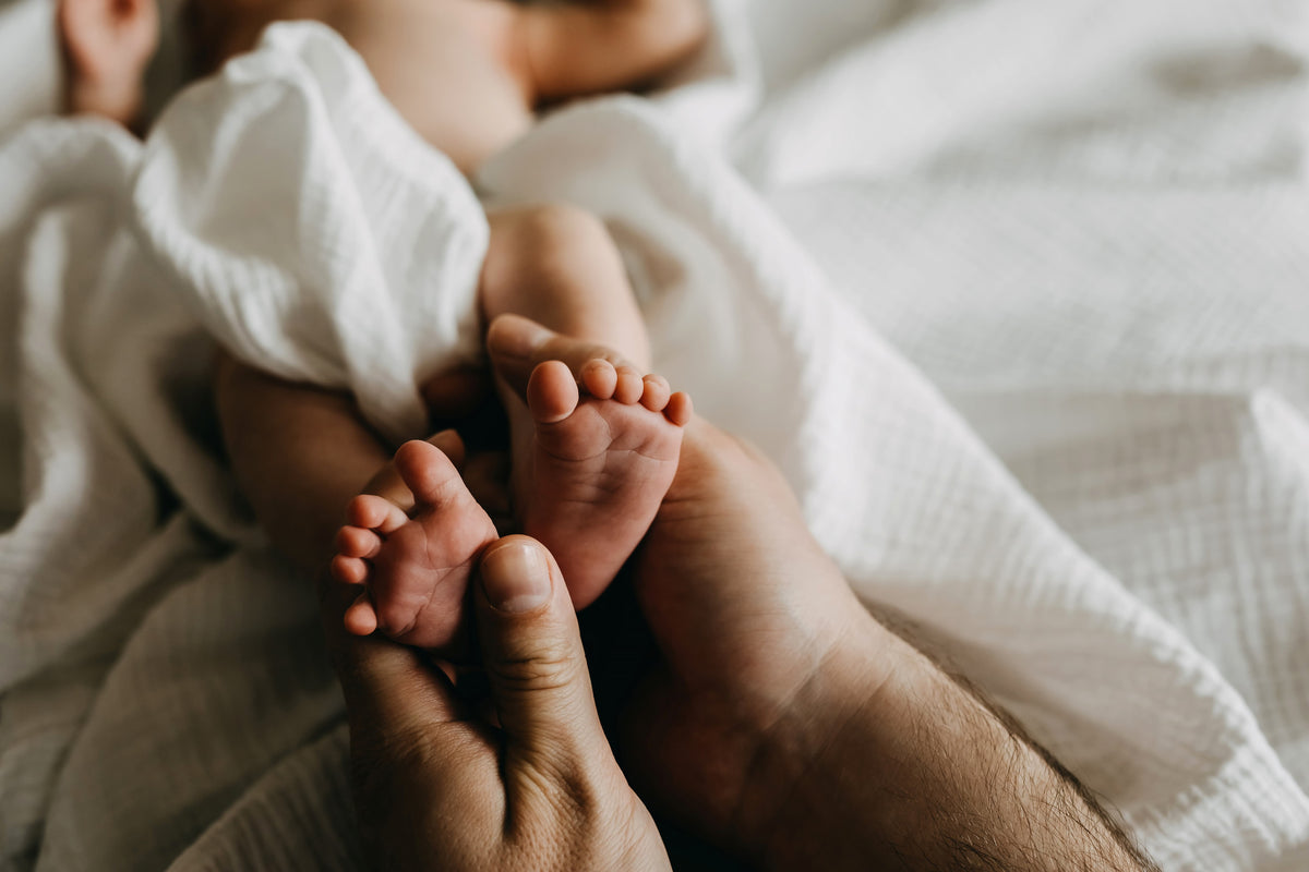 A mother holding her baby in a bright bedroom by a window