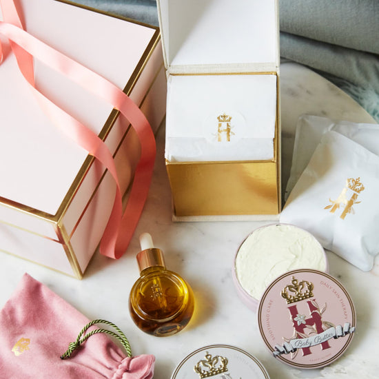 Pink gift box with a ribbon, a serum bottle, a pink pouch and two tins