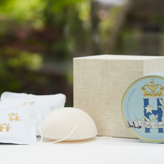 Butter in Blue tin, linen gift box, soak sachets and a konjac sponge in front of greenery