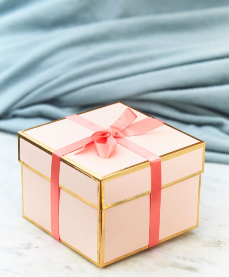 Pink gift box tied with a coral ribbon on a marble table