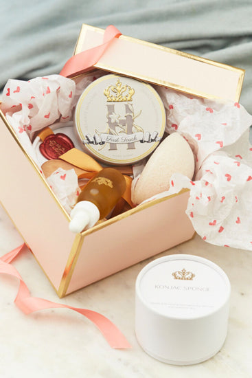 Open pink Royal Heir gift box with a butter tin, a serum bottle and a konjac sponge